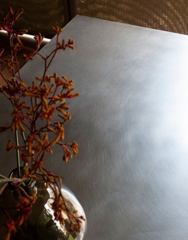 Détail d'une table en métal gris avec une composition florale en vase.