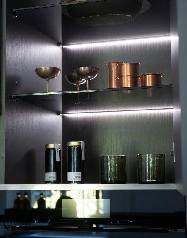 Détail intérieur de cuisine noire avec étagères marbrées et accessoires élégants.